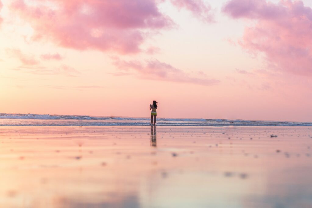 woman standing on seashore in front of body of water