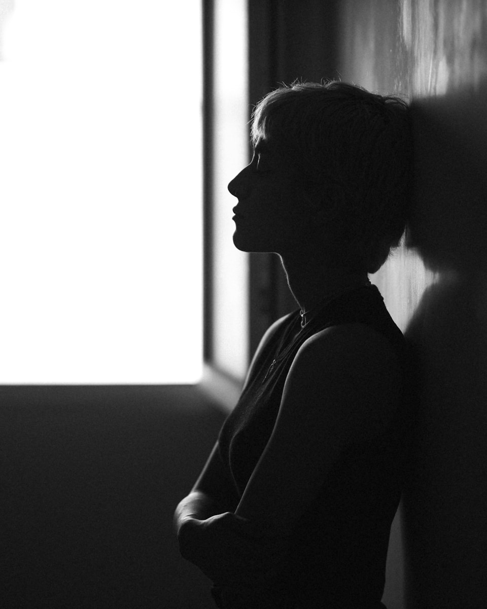 A silhouette of a woman leaning against a wall.